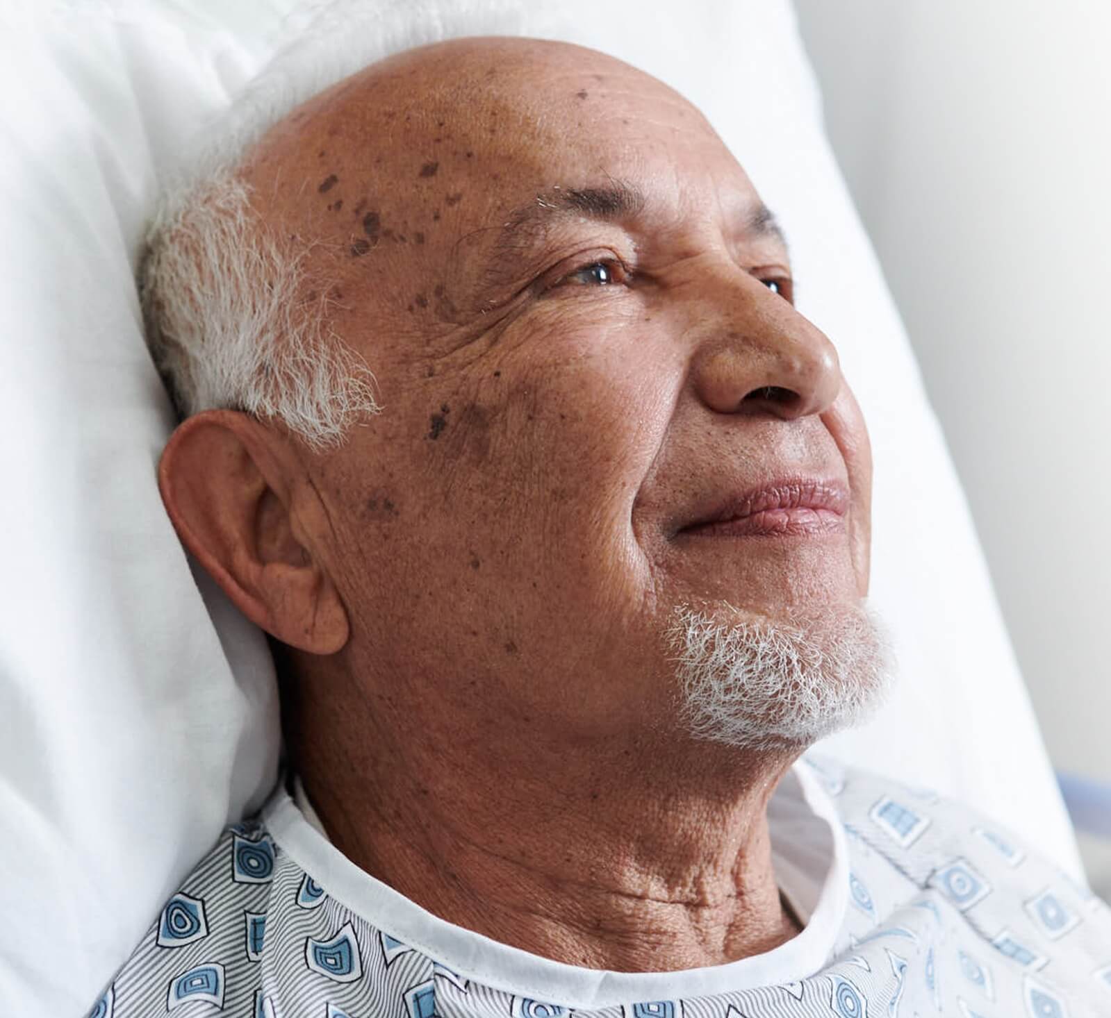 Elderly patient in bed smiling slightly.